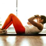 Young woman practicing yoga indoors, focusing on balance and fitness.