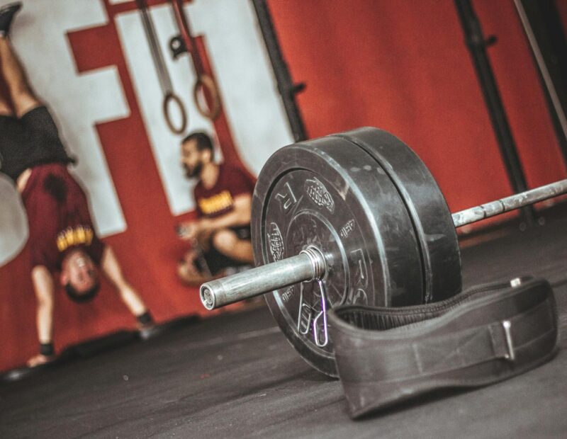 Dynamic gym scene featuring a barbell and fitness enthusiasts with intense workout energy.