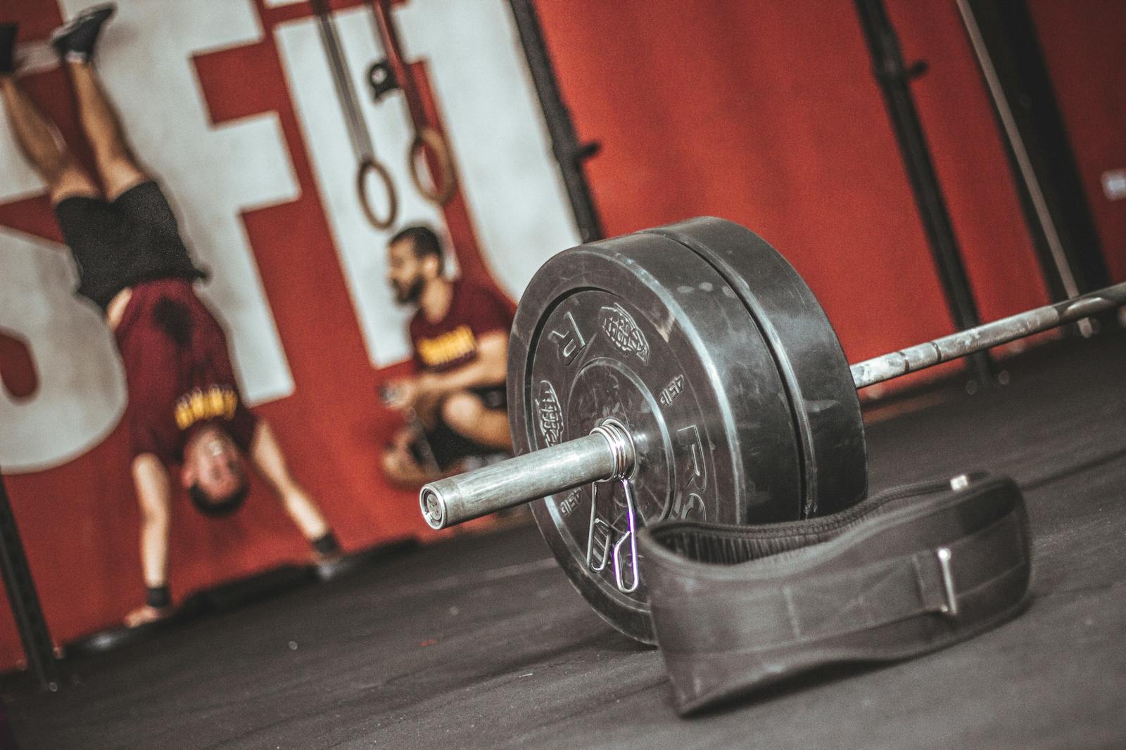 Dynamic gym scene featuring a barbell and fitness enthusiasts with intense workout energy.