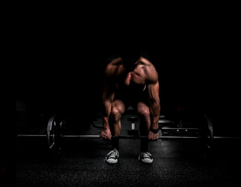 topless man in black shorts sitting on black and silver barbell